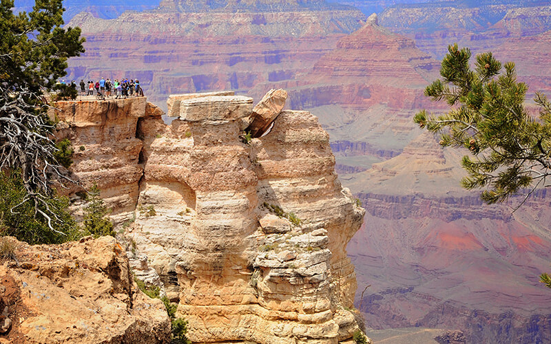 グランドキャニオンの展望地から景色を眺める旅行者